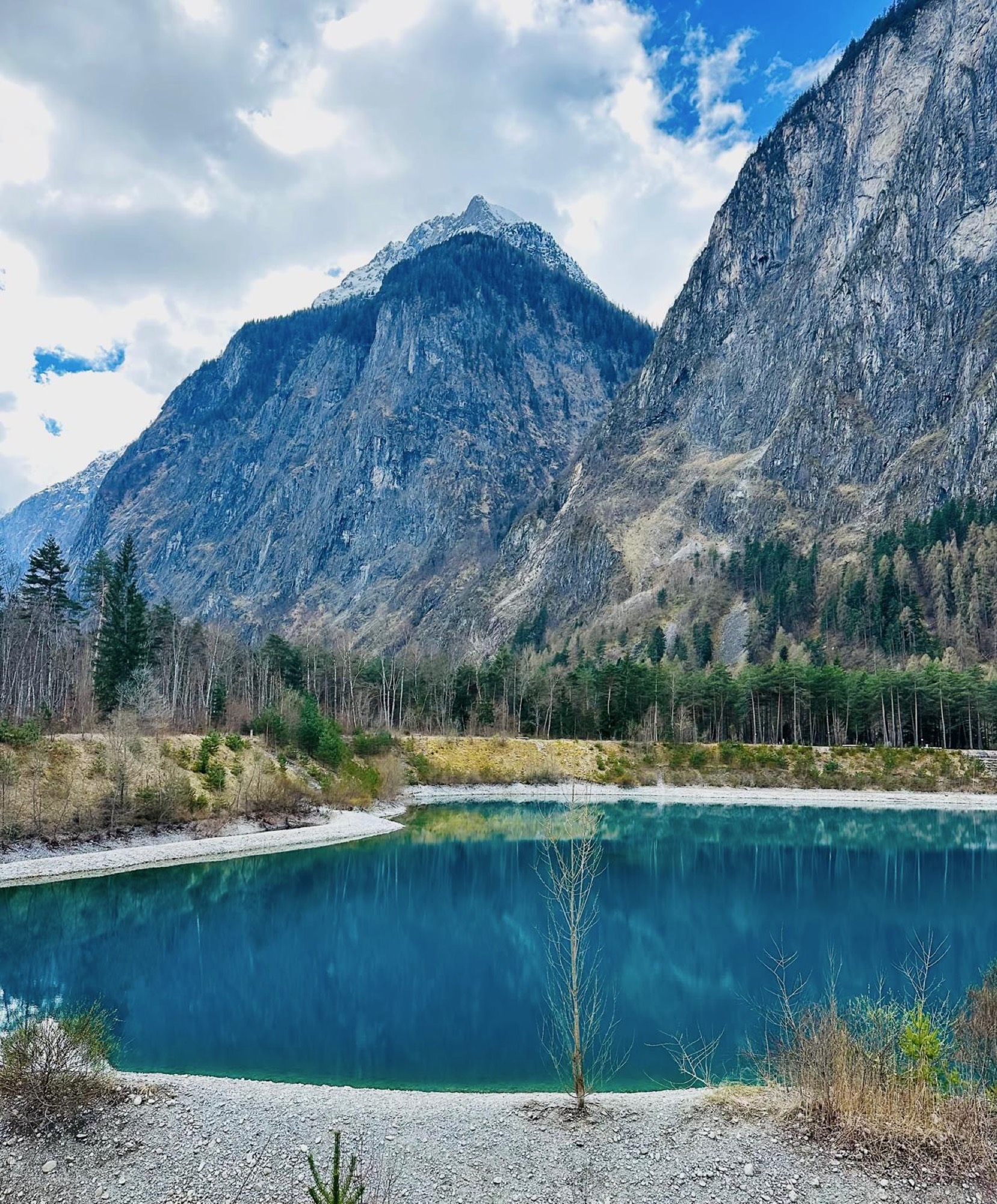 A still glacial lake beneath a forested mountain
