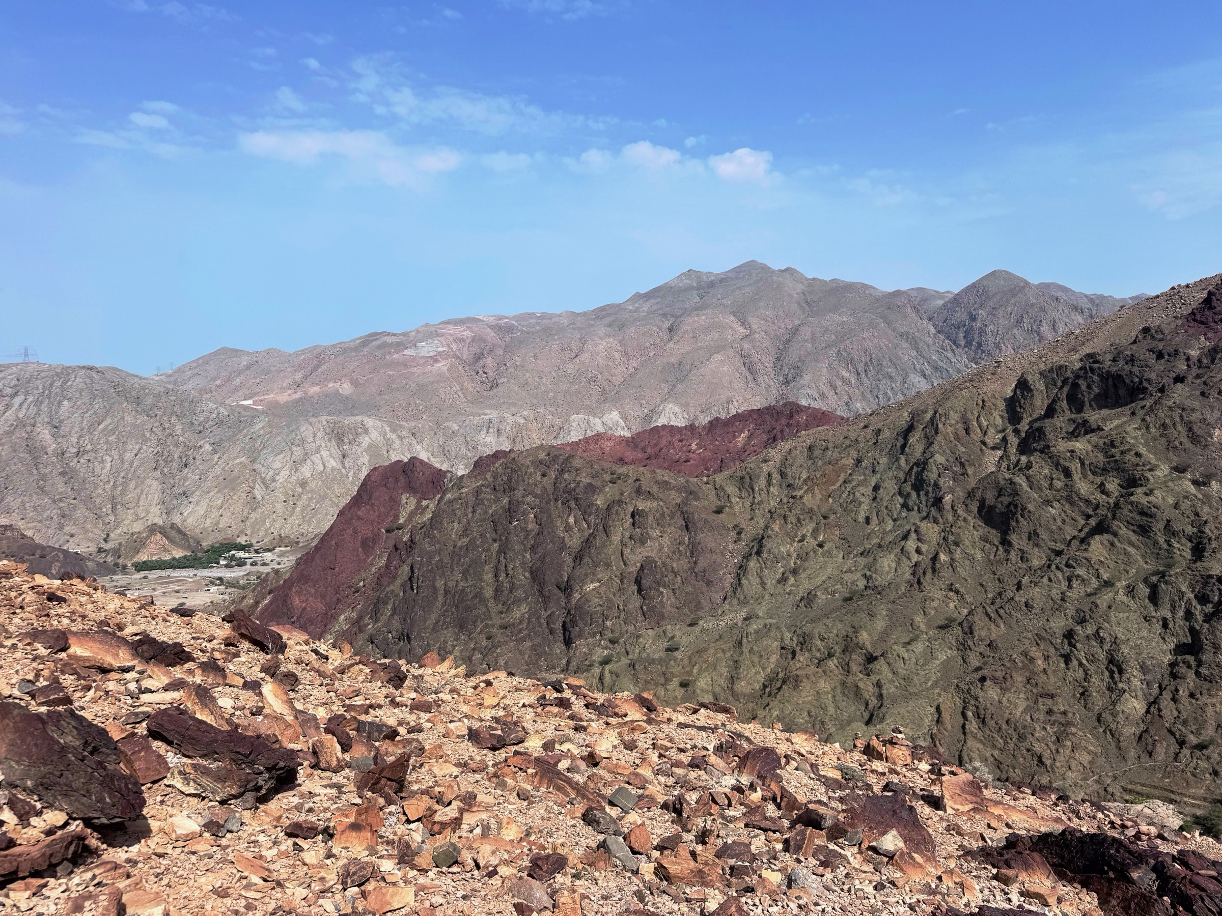 The arid Hajar mountains under a clear sky, the terrain of the Gulf
